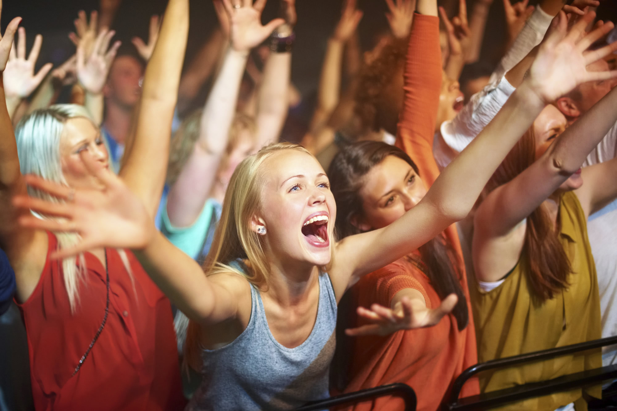 Crowd in front of stage at music concert with music artist client and musicians in band performing.
